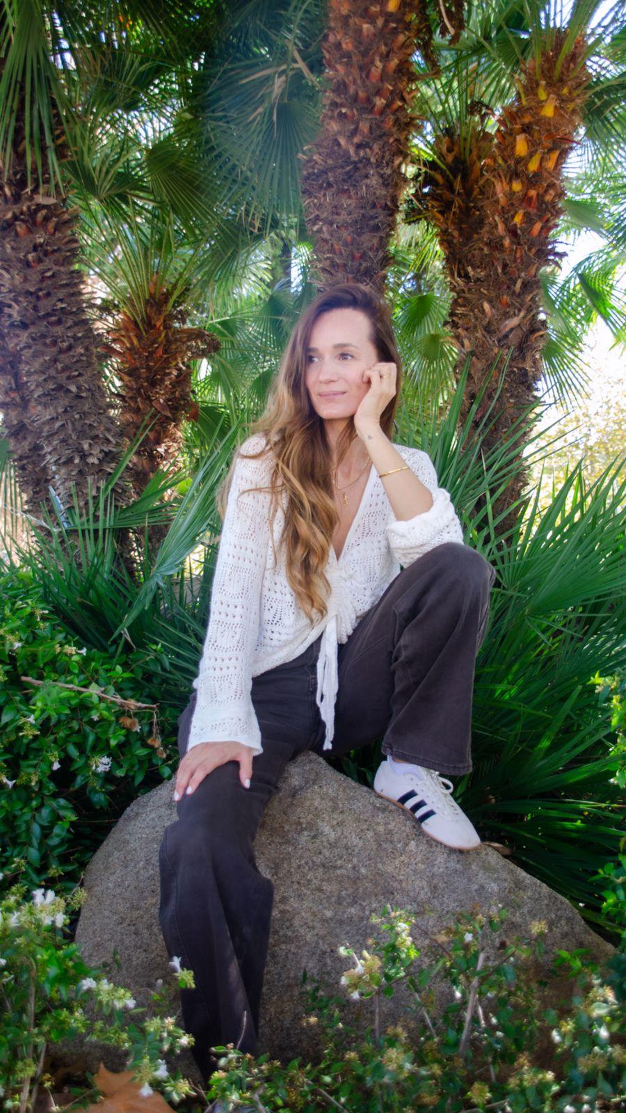 Anke in white, sitting on a rock under palm trees