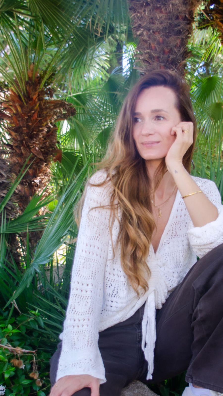 Anke in white, smiling, her hand in her hair