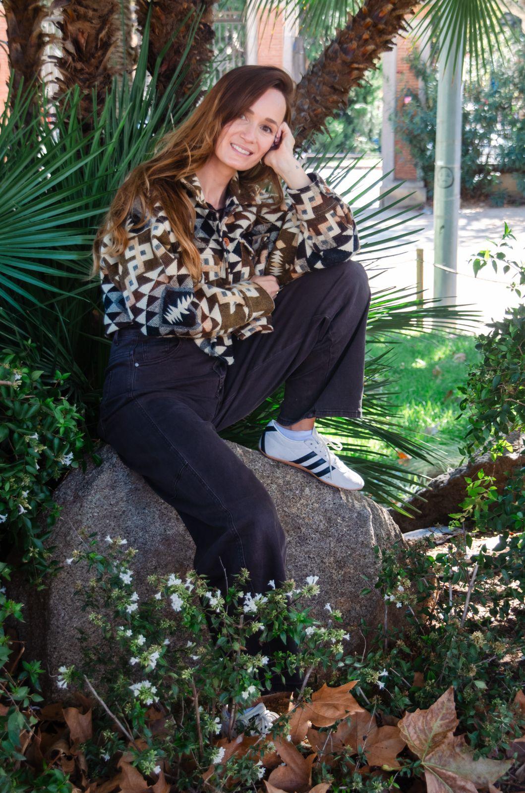 Anke smiling, sitting on a rock between palm leaves